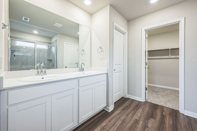 Bathroom featuring a stall shower, double vanity, a walk in closet, wood finished floors, and recessed lighting | Image 14