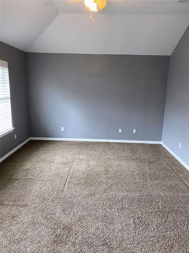 Spare room with baseboards, a ceiling fan, vaulted ceiling, and carpet flooring | Image 23