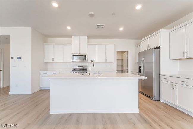 Kitchen featuring appliances with stainless steel finishes, light countertops, a center island with sink, light wood-style flooring, and recessed lighting | Image 10