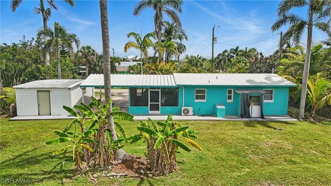 Back of property featuring a sunroom, a lawn, a metal roof, and a shed | Image 36