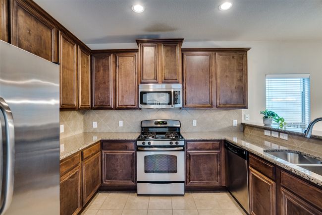 Kitchen with recessed lighting, light stone counters, backsplash, a sink, and appliances with stainless steel finishes | Image 9