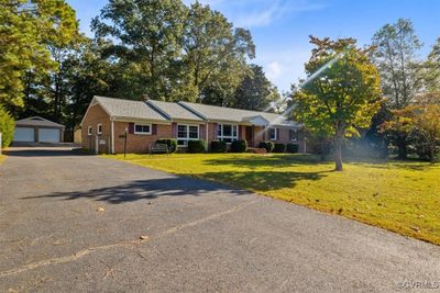 Ranch-style home featuring a garage, a front yard, and an outdoor structure | Image 2