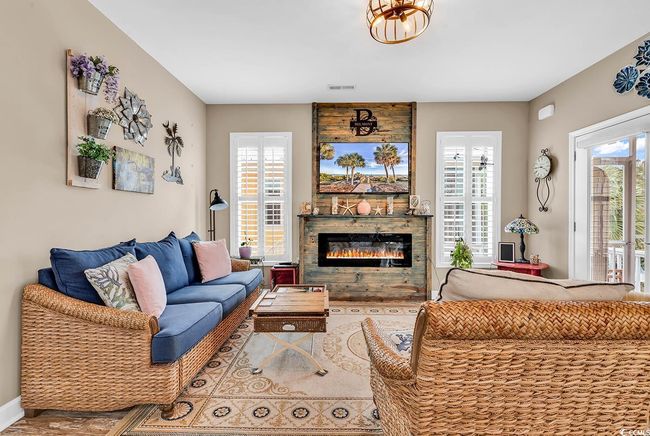 Living room with an inviting chandelier, a glass covered fireplace, a healthy amount of sunlight, and visible vents | Image 6