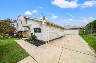 View of property exterior featuring a lawn, an outdoor structure, and a garage | Image 3