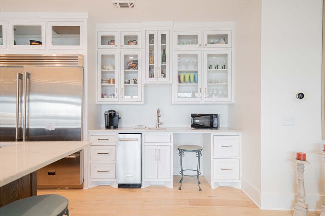 Kitchen featuring stainless steel built in refrigerator, white cabinetry, light wood-style floors, and glass insert cabinets | Image 20