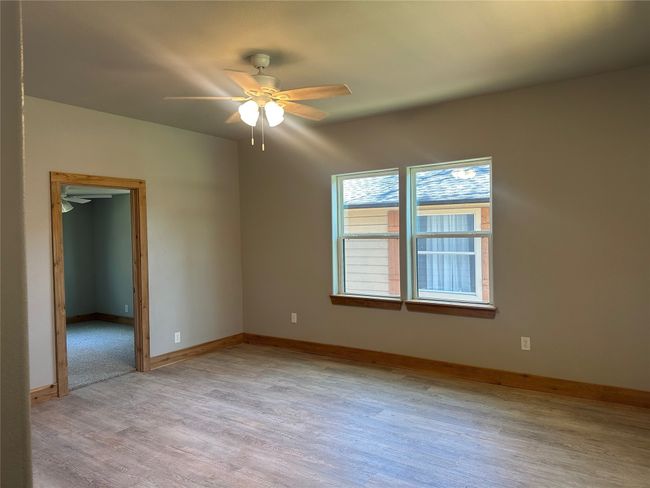 Empty room featuring baseboards, light wood-style floors, and a ceiling fan | Image 4