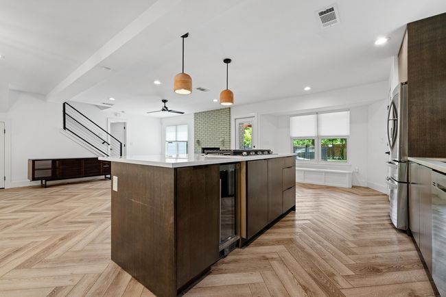 Kitchen with beverage cooler, light countertops, visible vents, a center island, and dark brown cabinetry | Image 18