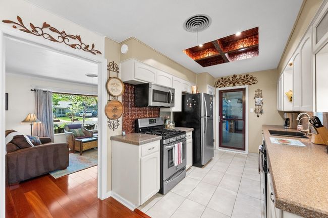 Kitchen with visible vents, white cabinets, a sink, stainless steel appliances, and light wood-style flooring | Image 12