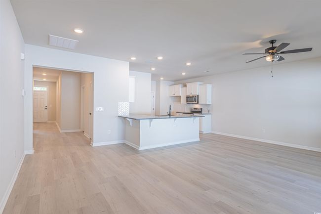 Kitchen with a kitchen bar, visible vents, appliances with stainless steel finishes, a peninsula, and white cabinets | Image 20