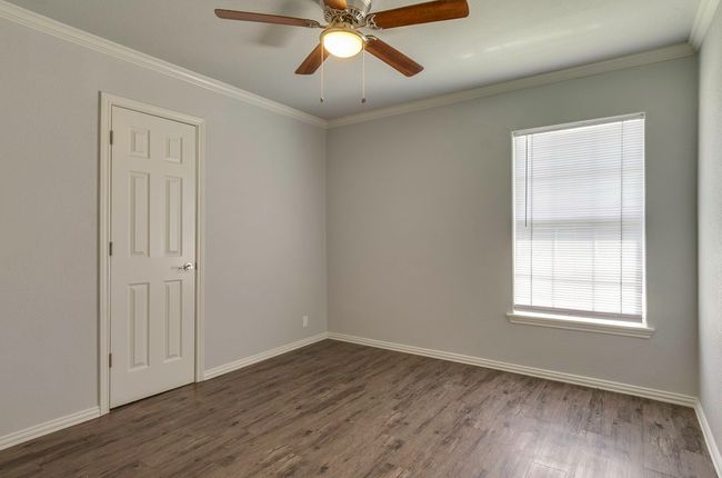 Empty room featuring dark wood finished floors, crown molding, and a ceiling fan | Image 29