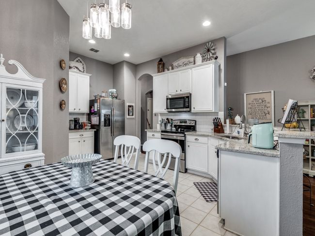 Dining space with arched walkways, a chandelier, light tile patterned floors, and recessed lighting | Image 13