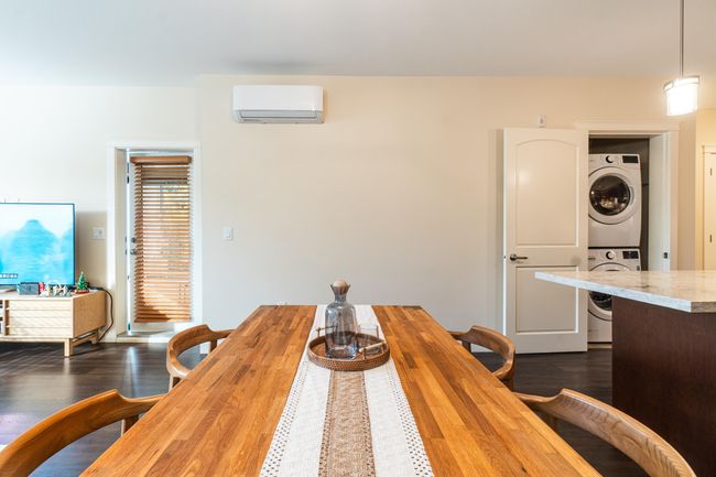 Dining room with stacked washer / drying machine, a wall mounted air conditioner, and dark wood finished floors | Image 13