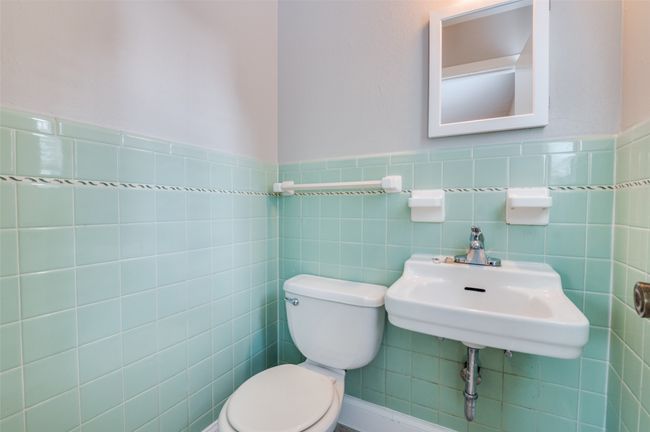 Half bath in Primary bedroom with toilet, sink and tile walls. | Image 22