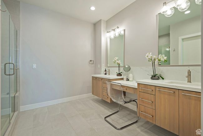 Bathroom featuring a shower stall, baseboards, two vanities, and a sink | Image 20