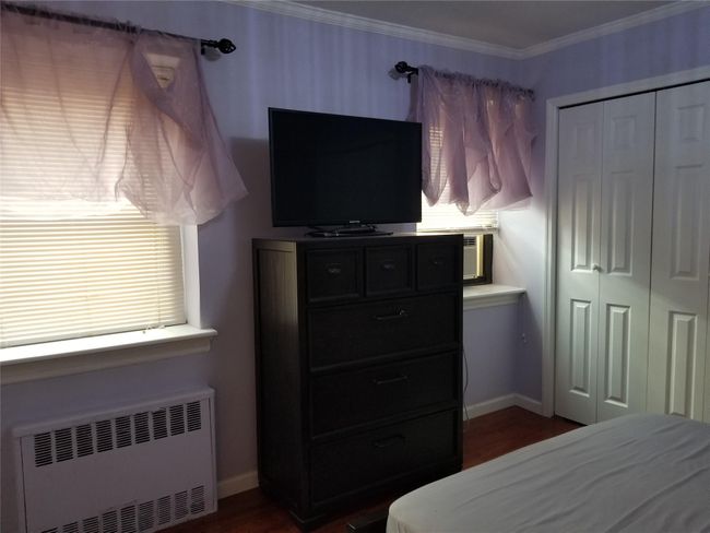 Bedroom featuring radiator heating unit, a closet, dark wood-type flooring, and crown molding | Image 13