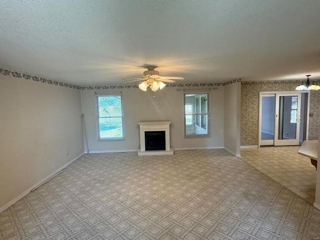 Unfurnished living room featuring a textured ceiling and ceiling fan with notable chandelier | Image 9