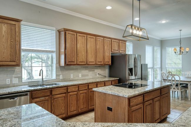 Kitchen featuring brown cabinetry, a sink, a chandelier, and appliances with stainless steel finishes | Image 10