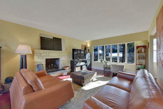 Living room featuring wood finished floors, a fireplace, and a textured ceiling | Image 5