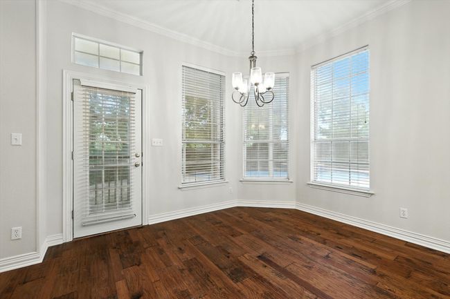 Unfurnished dining area with a chandelier, dark wood-style flooring, and crown molding | Image 8