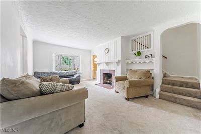 Living room with light colored carpet, a textured ceiling, and a brick fireplace | Image 3