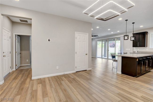 Kitchen with open floor plan, light countertops, a kitchen bar, light wood-type flooring, and recessed lighting | Image 9