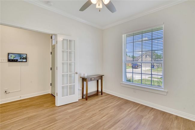 Empty room with light wood-style floors, ceiling fan, crown molding, and a smoke detector | Image 6
