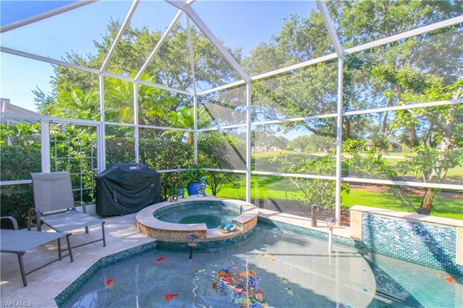 View of swimming pool featuring an in ground hot tub, glass enclosure, a patio area, and grilling area | Image 13