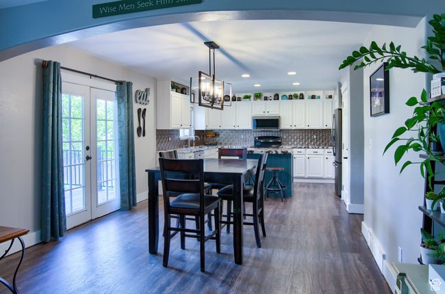 Dining space featuring baseboards, arched walkways, a chandelier, and dark wood-style flooring | Image 11