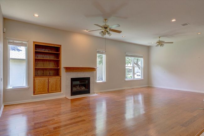 Unfurnished living room with built in shelves, ceiling fan, recessed lighting, a tile fireplace, and light wood-style floors | Image 8