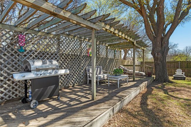 View of patio with a wooden deck, a pergola, fence, and a grill | Image 25