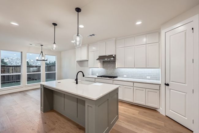 Kitchen with a sink, stainless steel gas stovetop, under cabinet range hood, visible vents, and decorative​​‌​​​​‌​​‌‌​‌‌​​​‌‌​​‌‌​‌​​​​​‌ backsplash | Image 9