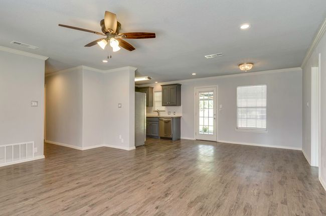 Unfurnished living room featuring a ceiling fan, dark wood-type flooring, recessed lighting, and ornamental molding | Image 9