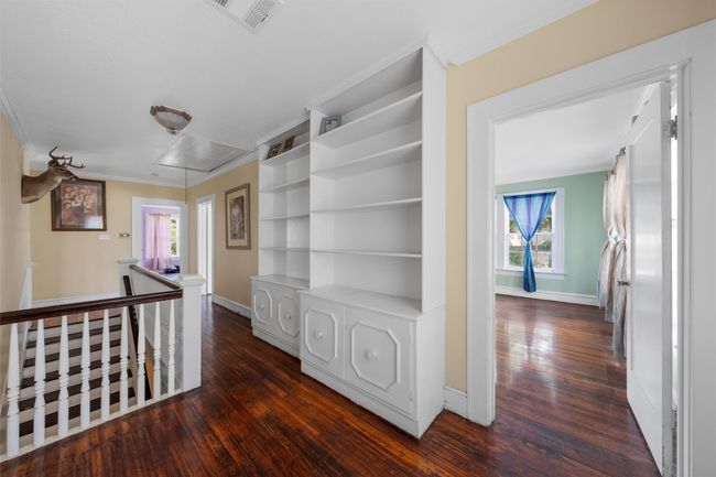 Hall featuring attic access, ornamental molding, an upstairs landing, dark wood-style flooring, and healthy amount of natural light | Image 20