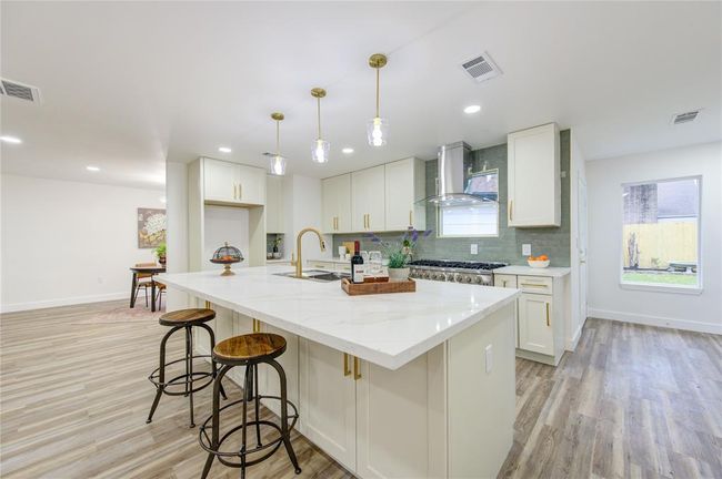 The island kitchen is designed for both style and functionality, featuring a large central island that serves as the heart of the space. The island offers extra storage with deep drawers and cabinets, providing plenty of room for kitchen essentials. | Image 12