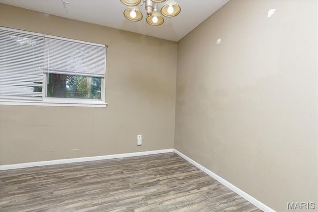 Spare room with a chandelier and wood finished floors | Image 9