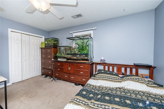 Bedroom with light colored carpet, a textured ceiling, a ceiling fan, and a closet | Image 16
