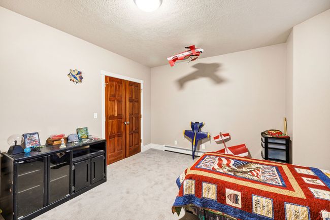 Carpeted bedroom featuring baseboard heating and a textured ceiling | Image 64