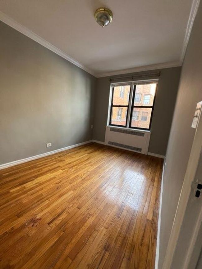 Spare room featuring crown molding, radiator heating unit, baseboards, and wood finished floors | Image 9