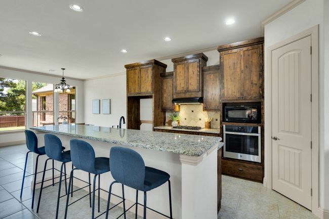 Kitchen with appliances with stainless steel finishes, tasteful backsplash, recessed lighting, a breakfast bar area, and ornamental molding | Image 9