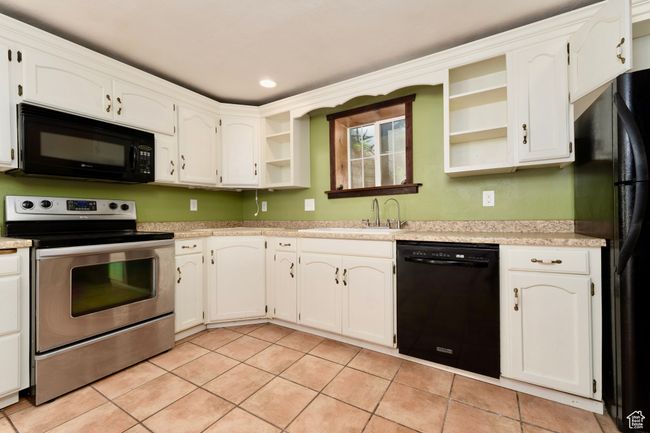 Kitchen featuring black appliances, open shelves, a sink, light tile patterned flooring, and light countertops | Image 30