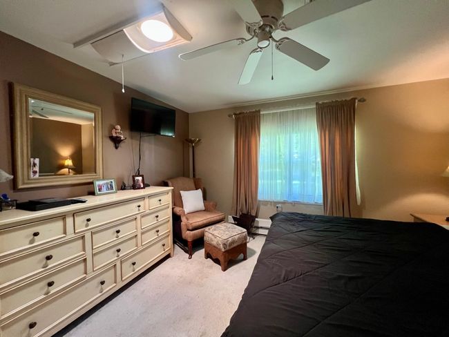Bedroom featuring light colored carpet, ceiling fan, and baseboard heating | Image 12