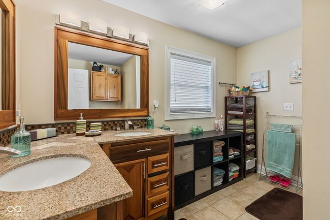 bathroom with tile patterned floors, double vanity, a sink, and backsplash | Image 27