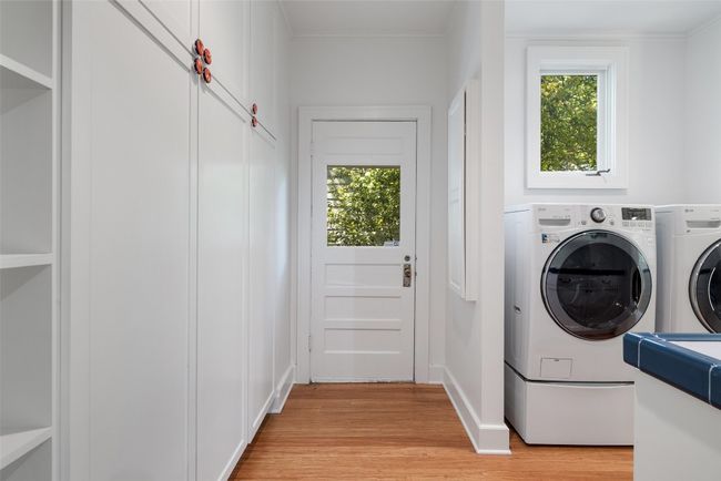 Clothes washing area with light wood-style floors, washing machine and clothes dryer, laundry area, and a wealth of natural light | Image 14