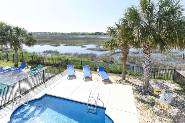 View of swimming pool featuring a water view, a patio area, and fence | Image 26