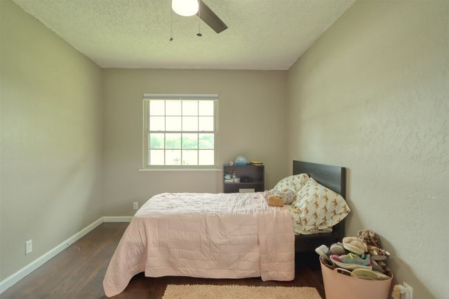 Bedroom featuring wood finished floors, a ceiling fan, and a textured ceiling | Image 33