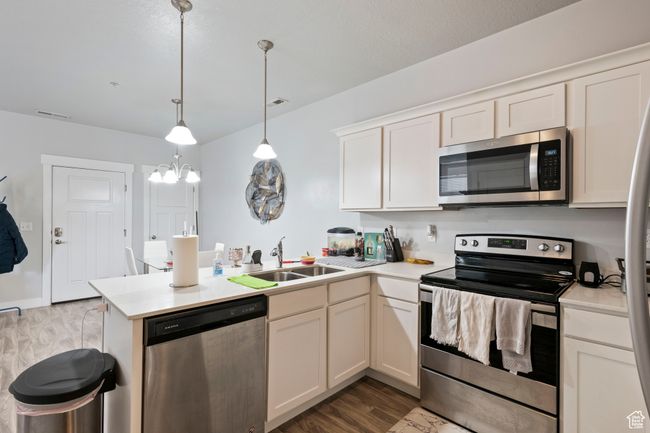 Kitchen featuring appliances with stainless steel finishes, a sink, a peninsula, and light countertops | Image 5
