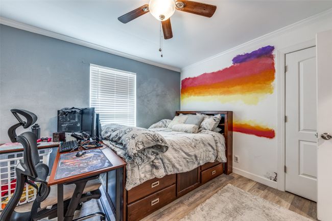 Bedroom featuring light wood-style floors, ornamental molding, ceiling fan, and an office area | Image 20