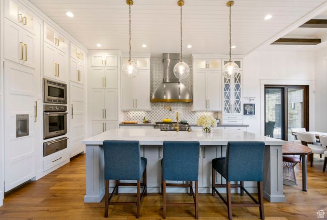 Kitchen with tasteful backsplash, wall chimney range hood, a warming drawer, stainless steel appliances, and dark wood-type flooring | Image 23