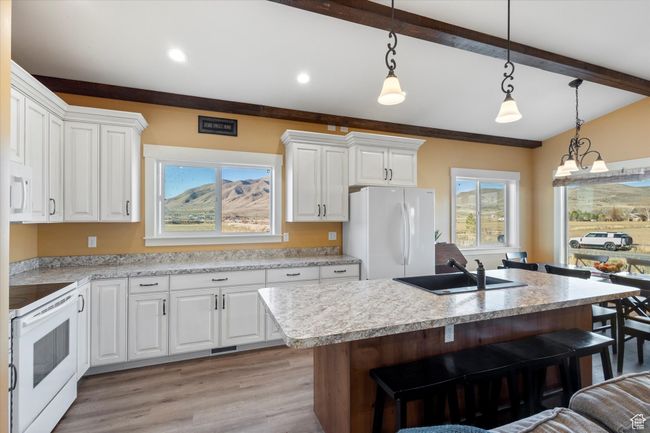 Kitchen with a sink, a kitchen breakfast bar, white appliances, and light countertops | Image 13