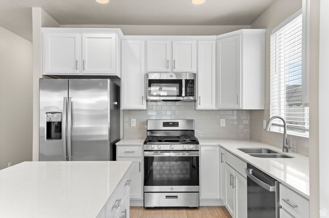Kitchen featuring white cabinets, stainless steel appliances, light countertops, and a sink | Image 16